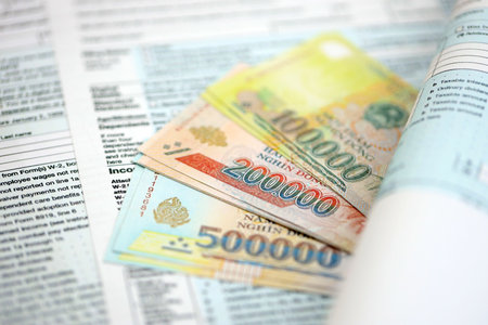 Vietnamese dong money bills on tax form close up. Taxation and accounting conceptの写真素材