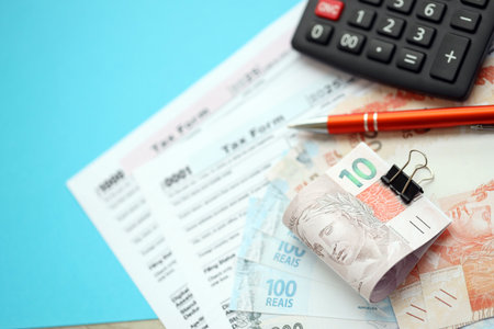 Brazilian reais banknotes with calculator and tax form. The current Brazil real money bills and tax blank close up. The concept taxpaying and accounting in Brazilの写真素材