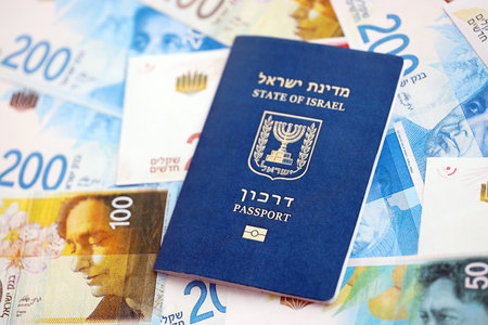 Israel New Shekels banknotes and passport. The current Israel money bills and biometrical pass lies on table in big amount. The concept of travel and vacation in Israelの写真素材
