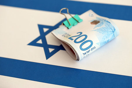 Israel New Shekels banknotes on national flag. The current Israel money bills lies on flag in big amount. The concept of business and investment in Israelの写真素材