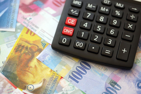 Swiss franc banknotes and calculator. The current francs money bills and calc lies on table in big amount. The concept of taxation and money count in Switzerlandの写真素材