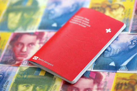 Swiss franc banknotes and passport. The current francs money bills and biometrical pass lies on table. The concept of travel and vacation in Switzerlandの写真素材