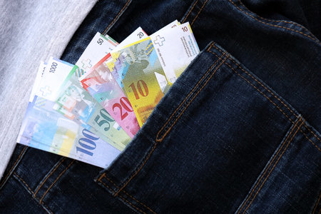 Swiss franc banknotes in denims pocket. The current francs money bills lies in jeans pocket. The concept of fashion and wealth in Switzerlandの写真素材