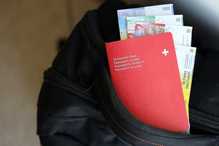 Swiss passport and franc money bills on travel bag. Pass and banknotes on bag close up. The concept of travel and vacation in Switzerlandの写真素材