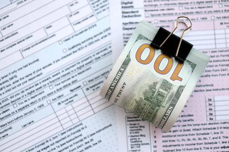 Big amount of United States dollar bills on table with individual income tax return form close up. Concept of taxation and accounting in United Statesの写真素材