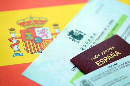 Spanish passport lies on citizenship or naturalization documents on flag of Spain close upの写真素材