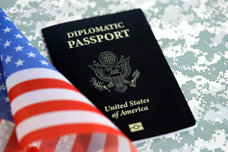 United States diplomatic passport book with US flag on camouflage fabric close up. Travel document on camo photoの写真素材