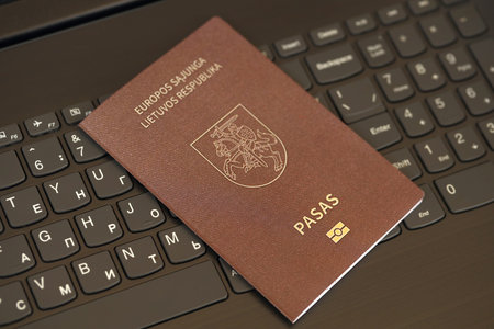Lithuania passport lies on black laptop keyboard buttons background close up. Technologies and control in Europe conceptの写真素材