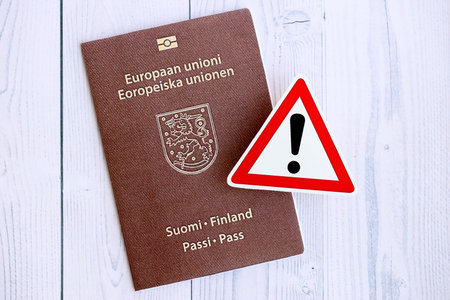 Finland passport with exclamation sign on white wooden background close up. Problems with citizenship in Europe conceptの写真素材