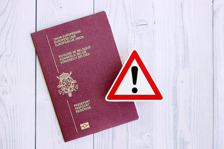Belgium passport with exclamation sign on white wooden background close up. Problems with citizenship in Europe conceptの写真素材