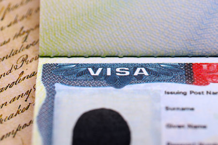 Close-up view of a us visa stamped on a passport page with US Constitution background. Travel and...
