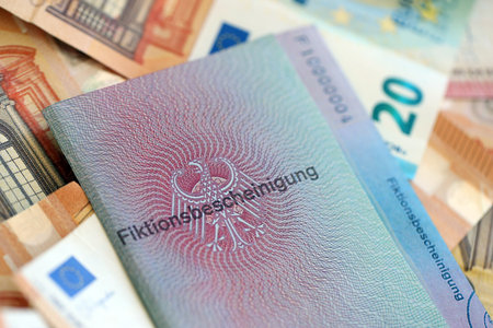 German temporary Permanent resident card specimen and euro money bills lies on wooden table close up. Fiktionsbescheinigungの写真素材