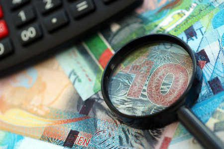 Kuwaiti dinar currency money bills and calculator with magnifying glass close up. The concept of...