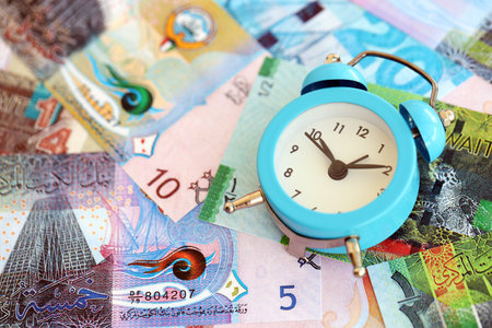 Kuwaiti dinar currency money bills and alarm clock close up. The concept of time management and incomeの写真素材