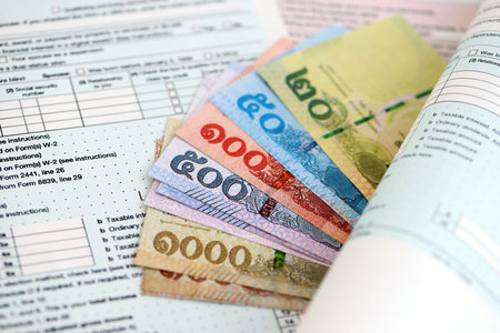 Thai baht money bills on tax form close up. Taxation and accounting conceptの写真素材