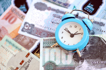 Egyptian pound currency money bills and alarm clock close up. The concept of time management and incomeの写真素材