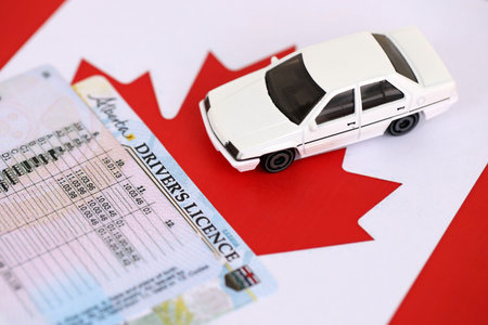 Canadian driving permit concept. Toy car and driver license on flag close upの写真素材