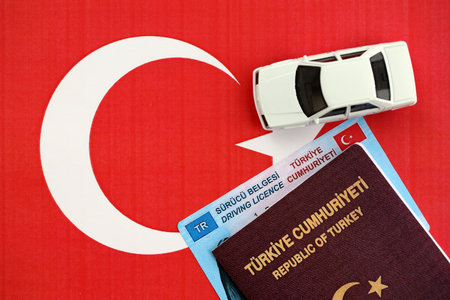 Turkiye driving permit concept. Driver license with passport and toy car on turkish flag close upの写真素材