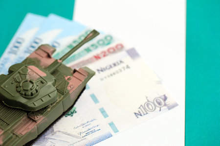 Nigerian naira currency money bills and toy tank on flag close up.の写真素材
