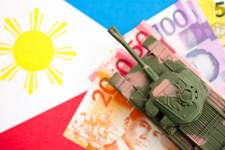 Philippines peso currency money bills and toy tank on flag close up.