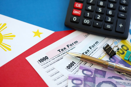 Philippines peso money bills and calculator with tax form on flag close up. Taxation and accounting conceptの写真素材