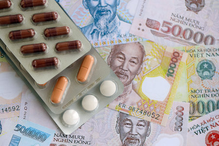Vietnamese dong currency money bills and medicine pills close up. The concept of medicine and pharmacyの写真素材