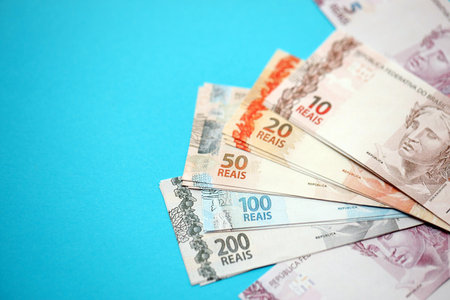 Close up of brazilian reais money bills in big amount on blue table. Pile of Brazil real currency banknotes. Finance and banking conceptの写真素材