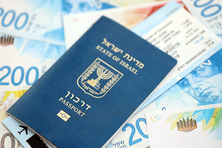 Israel New Shekels banknotes and passport. The current Israel money bills and biometrical pass lies on table in big amount. The concept of travel and vacation in Israelの写真素材
