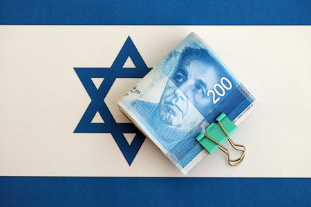Israel New Shekels banknotes on national flag. The current Israel money bills lies on flag in big amount. The concept of business and investment in Israelの写真素材