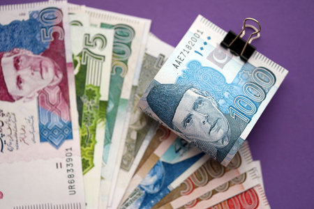 Pakistan rupees banknotes on purple background. The current Pakistan money bills lies on table in...