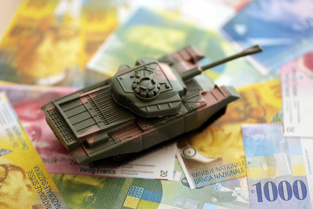 Swiss franc banknotes and toy tank. The current francs money bills and tank lies on table in big amount.の写真素材