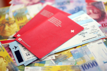 Swiss franc banknotes and passport with tickets. The current francs money bills and biometrical pass lies on table in big amount. The concept of travel and vacation in Switzerlandの写真素材