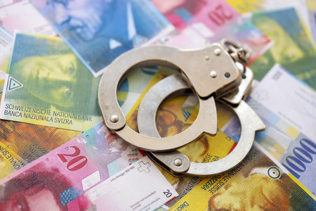 Swiss franc banknotes and handcuffs. The current francs money bills and cuffs lies on table in big amount.の写真素材