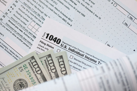Hundred dollar bills and 1040 individual income tax return form blank close up. Few usd notes and united states tax blank. Concept of taxpaying and accounting in United Statesの写真素材