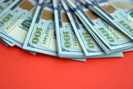 Big amount of United States hundred dollar bills on red background. Concept of taxation and money makingの写真素材