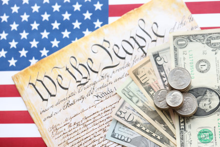 American US dollars money bills with coins and constitution close up on american flag. The American...