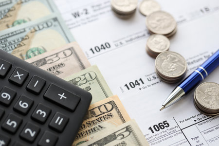 American US dollars money bills and coins with pen and calculator on IRS tax form blanks close up. Accounting and taxpaying period conceptの写真素材
