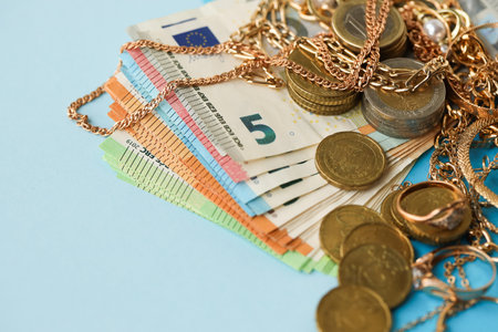 European union Euro money bills and coins with golden rings and jewelry necklaces on blue table close upの写真素材