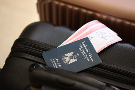 Palestinian Authority passport with tickets lies on touristic suitcase close up in airport waiting hall. Travel worldwide and international tourism conceptの写真素材