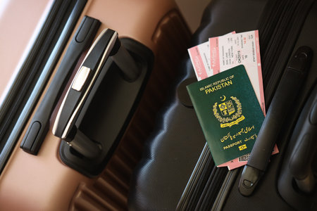Islamic Republic of Pakistan passport with tickets lies on touristic suitcase close up in airport waiting hall. Travel worldwide and international tourism conceptの写真素材