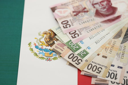 Mexican pesos money bills in big amount lies on Mexico flag close up. Finance and banking conceptの写真素材