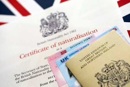 British emergency passport and Certificate of Naturalisation. Yellow color temporary document with residence permit card and driving license close upの写真素材
