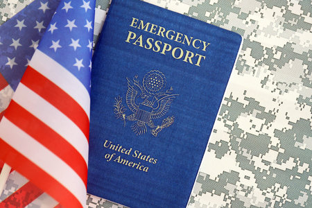 United States emergency passport book with US flag on camouflage uniform close up. Travel document on camo fabric photoの写真素材
