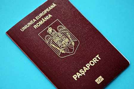 Romanian passport book on light blue paper background close up. Travel document on blue surfaceの写真素材
