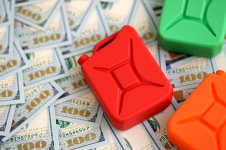 Petroleum or gasoline canister reservoir lies on big amount of dollar bills. Concept of petrol prices in United Statesの写真素材