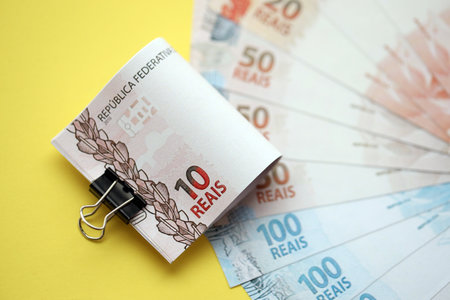 Close up of brazilian reais money bills in big amount on yellow table. Pile of Brazil real currency...
