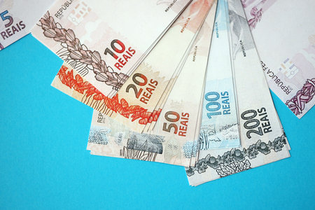 Close up of brazilian reais money bills in big amount on blue table. Pile of Brazil real currency...