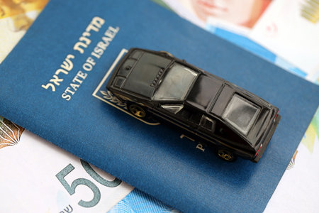 Israel New Shekels banknotes and toy car with passport. The current Israel money bills and black car with pass lies on table in big amount. The concept of car ownership in Israelの写真素材