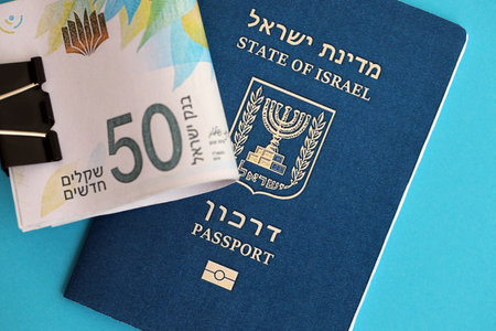 Israel New Shekels banknotes and passport on blue background. The current Israel money bills lies on...