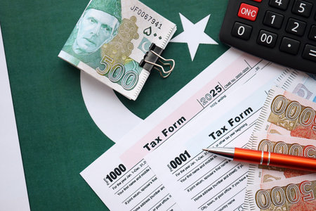 Pakistan rupees banknotes with calculator and tax form. The current Pakistan real money bills and tax blank close up. The concept taxpaying and accounting in Pakistanの写真素材